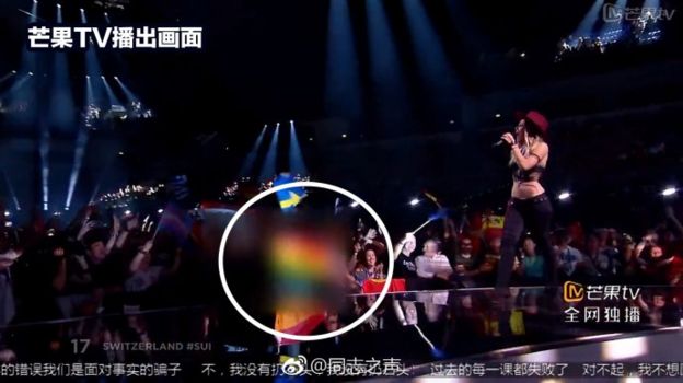 Screenshot of Switzerland's Eurovision performance with a rainbow flag in the audience blurred out and circled