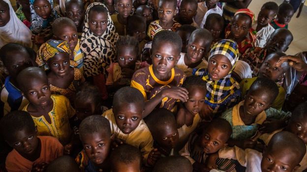 A group of children are seen posing in their classroom for a photo in the remote village of Kpalong