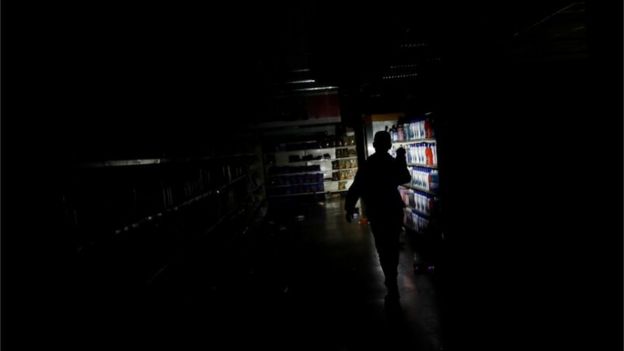 A worker inspects damage in a supermarket after it was looted during an ongoing blackout in Caracas, Venezuela March 10, 2019.