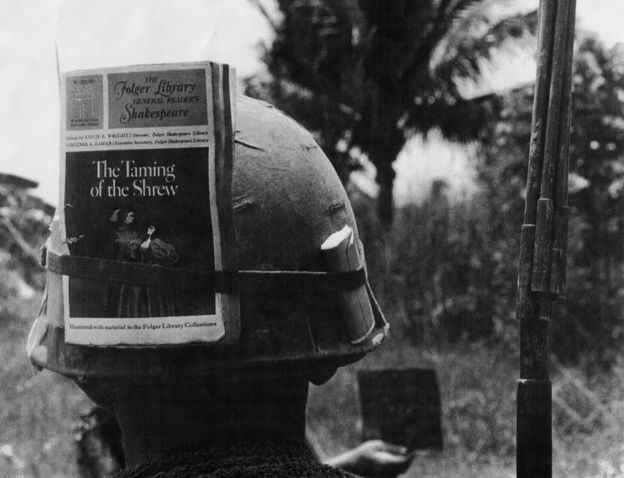 American soldier in Vietnam with a copy of the Folger Shakespeare edition of The Taming of the Shrew tied to his helmet