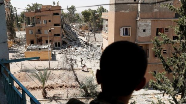 A Syrian Democratic Forces (SDF) fighter stands on a balcony overlooking Raqqa