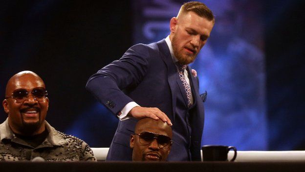 Conor McGregor puts his hand on Floyd Mayweather's head