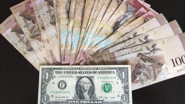 Un billete de dólar y el equivalente en bolívares en el mercado paralelo