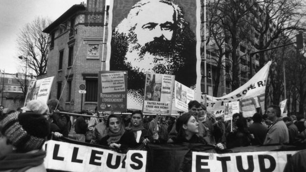 Foto de manifestantes en Francia en 1955 llevan un estandarte de Marx.