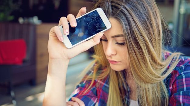 Joven con celular quebrado.