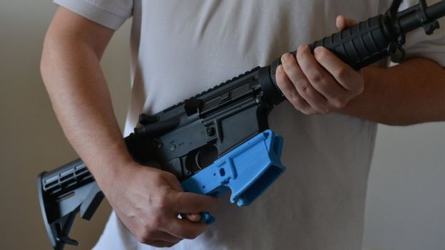 A plastic lower receiver is held next to an AR-15 rifle