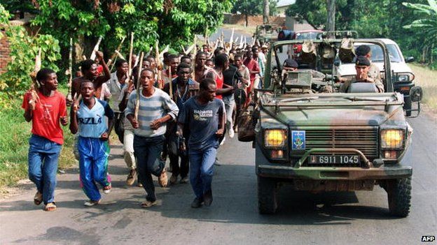 French troops driving past Hutu militiamen