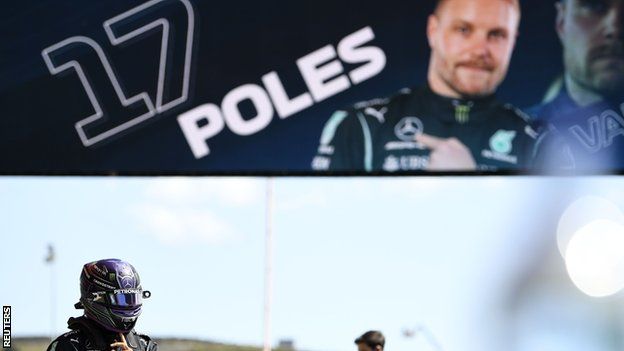 Lewis Hamilton walks past a sign that shows Valtteri Bottas with 17 pole positions