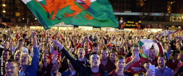 Supporters waving Wales flags celebrate in one of the World Cup fan zones