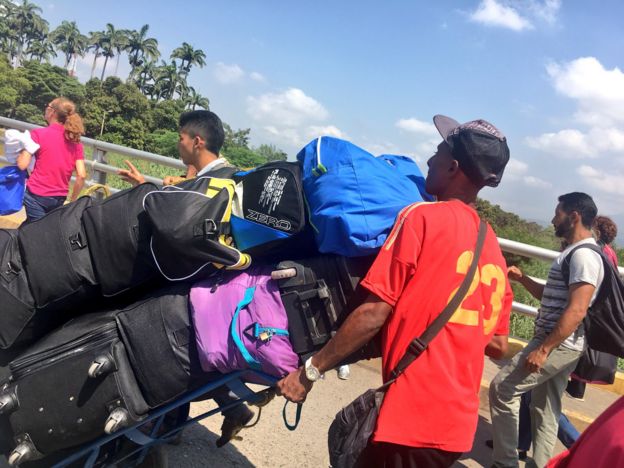 Personas cruzando la frontera con sus maletas