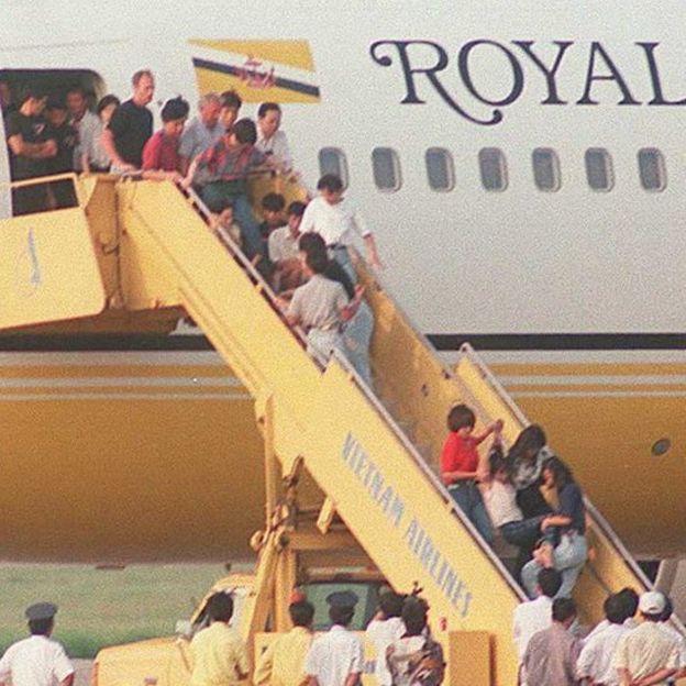 Không phải lần đầu tiên bị ép trở về: Một người phụ nữ bị kéo đi trong khi những người khác thì ngồi lỳ trên thang nối máy bay từ chối rời đi. Đây là nhóm 100 người Việt bị trục xuất khỏi Hongkong sau khi Anh Quốc và Việt Nam ký thỏa thuận năm 1995.