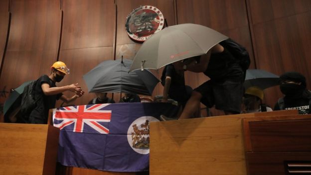 Protesters fix a British colonial flag to the parliament podium after they broke into the government headquarters in Hong Kong on July 1, 2019,