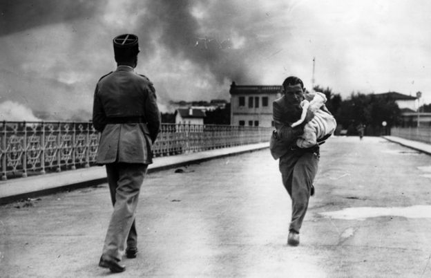 Journalist Raymond Walker risks his life under a hail of bullets dashing across the international bridge from Hendaye, France, to Irun, Spain to save a baby, during the Spanish Civil War