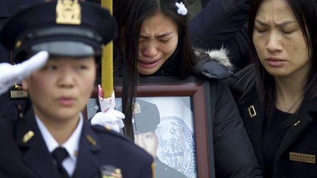Wenjian Liu's widow, Pei Xia Chen, weeps while clutching a photo of the dead policeman at his funeral in New York, 4 January