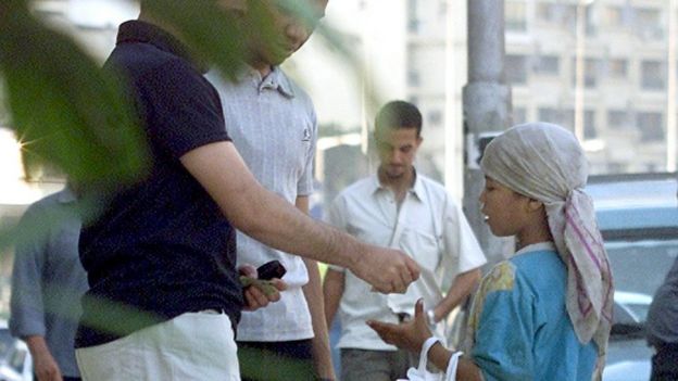 Des hommes donnent de l'argent à une jeune mendiante au Caire (file photo)