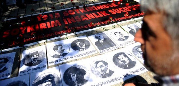 A person looks at portraits and a sign reading "1915 is a Genocide. Genocide is a crimes against humanity" during a demonstration on 24 April 2013 in Istanbul