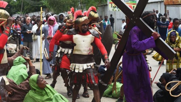 A man enacting Jesus Christ receives a beating as he carries a cross during a procession to mark Good Friday in Lagos, on April 14, 2017.