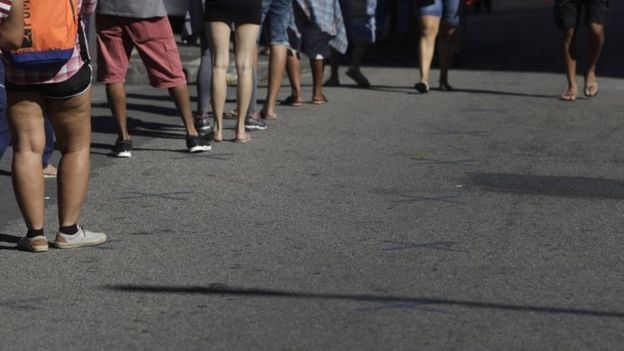 Pernas de pessoas enfileiradas na rua