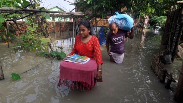 Villagers move to a safer place from the flooded area of Hatisela in Kamrup district of Assam.
