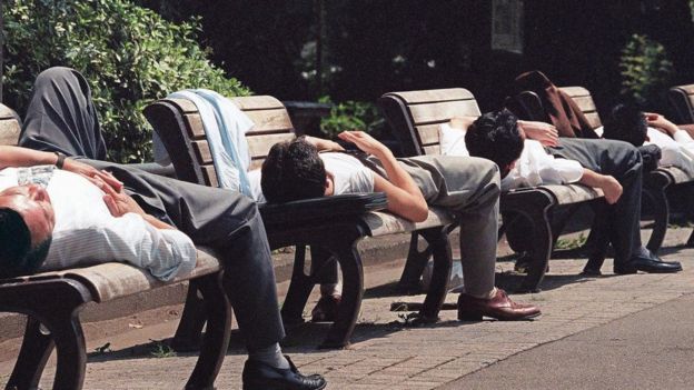 Homens japoneses deitados em bancos de praça