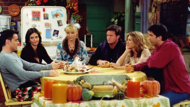 Cena do seriado Friends, com os seis personagens principais sentados em uma mesa no Dia de Ação de Graças