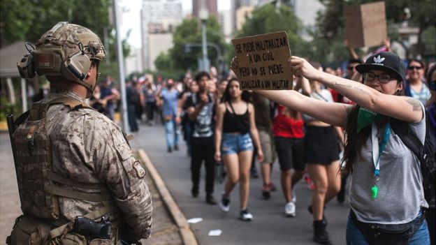 Manifestantes y militar en Chile