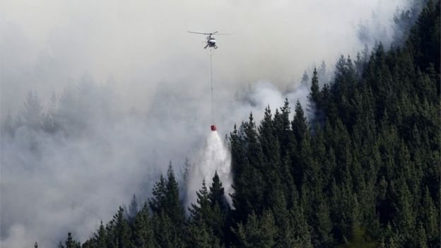 A helicopter drops water on a forest fire in Port Hills, New Zealand (14 Feb 2017)