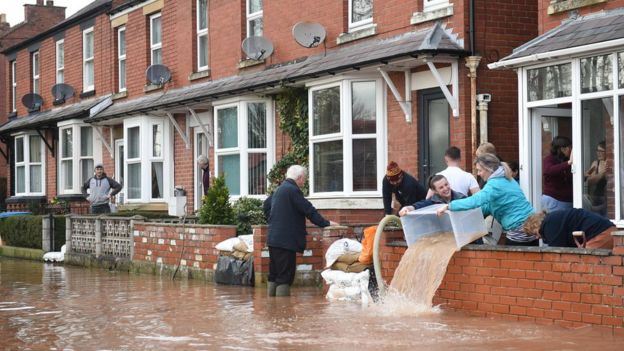 People bail water out of flooded homes after the River Wye burst its banks in Ross-on-Wye, western England, on February 17, 2020,