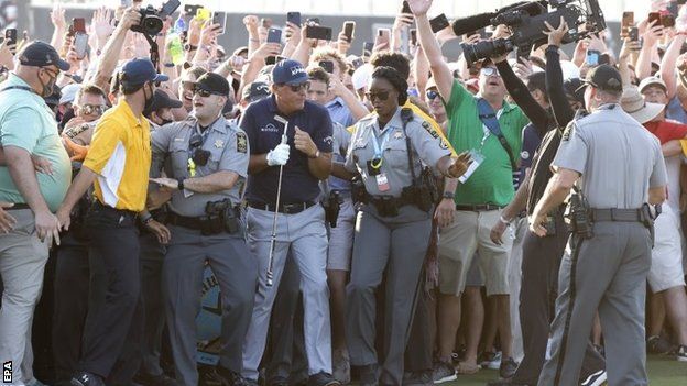 Phil Mickelson emerges through the crowd on to the 18th green