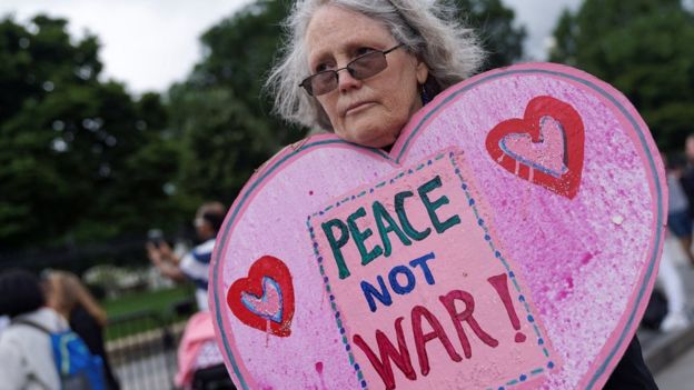 Una mujer con un cartel de "Paz, no guerra"