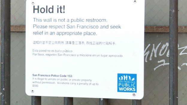 Sign warning people not to urinate against wall