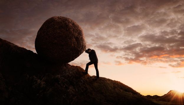 Un hombre empujando una piedra