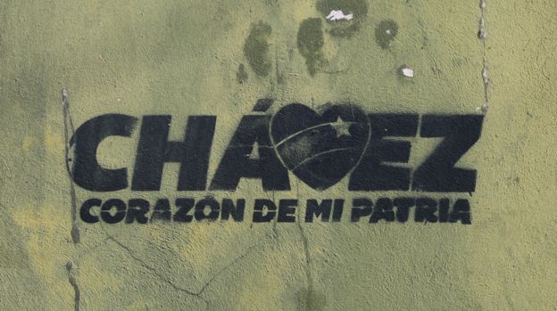 A stencil on a wall reads "Chávez, the heart of my homeland"