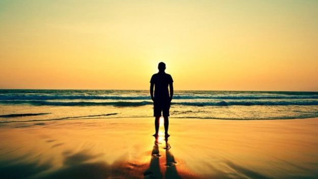 شاب يقف وحيدا أمام شاطئ البحر