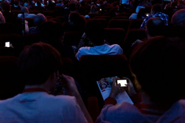 Penonton memakai ponsel di dalam teater bioskop