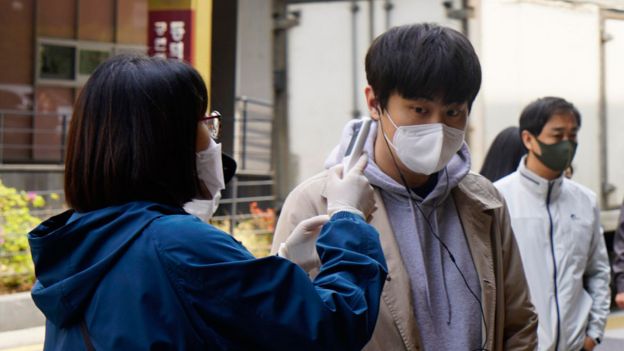Una mujer chequea la temperatura de un hombre en Corea del Sur
