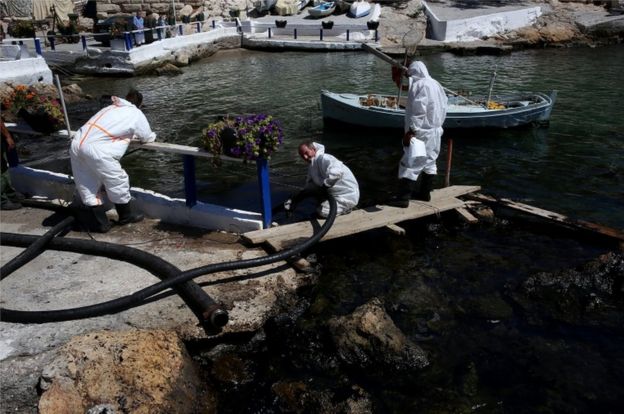 Workers deploy a hose to remove oil from a pretty bay near Athens on 13 September 2017