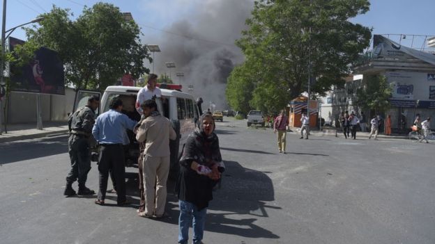 Heridos son trasladados en ambulancia mientras se ve el humo en el fondo.