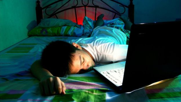 A child with a computer in bed