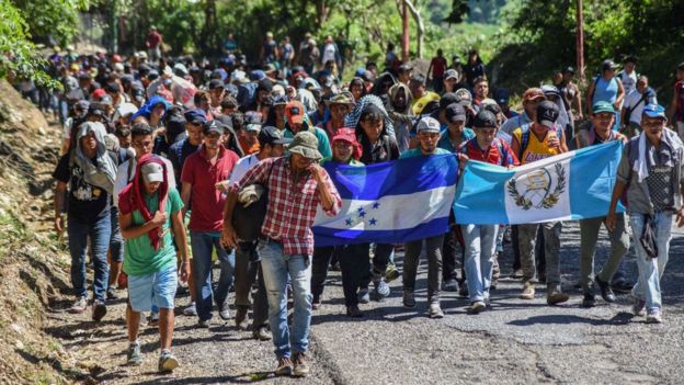 Migrantes marchan con banderas al frente