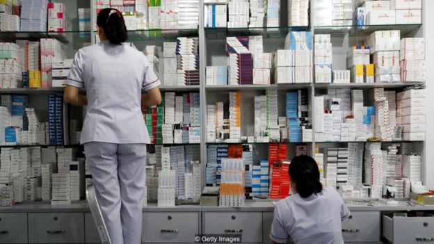 Duas funcionárias organizam caixas de remédios em farmácia
