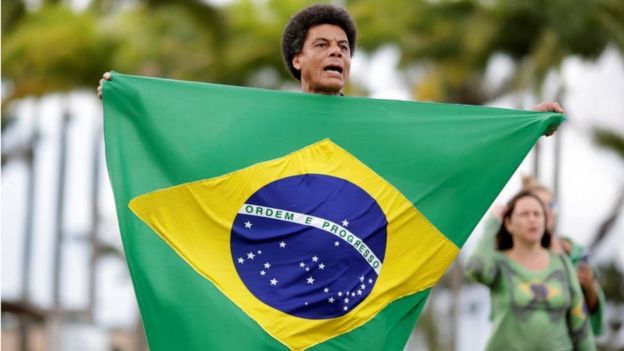 Hombre sostiene una bandera de Brasil.