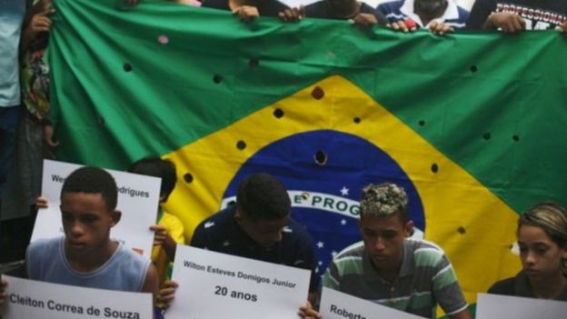 Bandeira do Brasil com buracos para representar tiros de 111 balas disparadas contra 5 jovens no Rio, em 2015