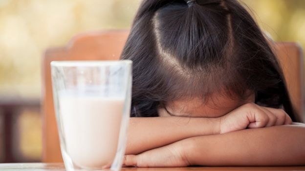 Niña negándose a comer la leche.