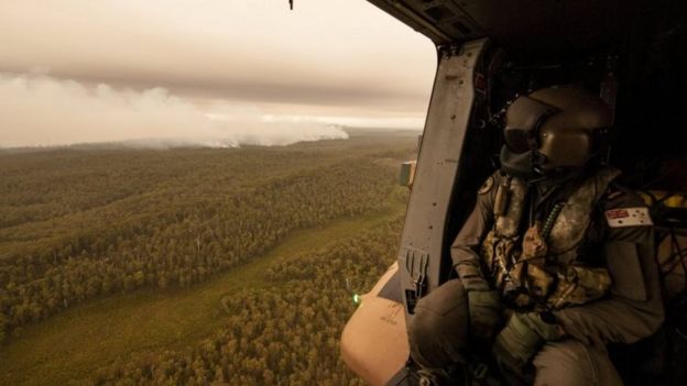 A navy helicopter flies over a bushfire in Victoria