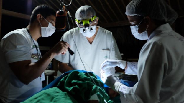 equipe médica faz atendimento sob luz de lanterna