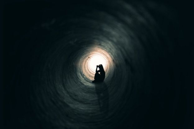 Silueta de una mujer sentada en un túnel