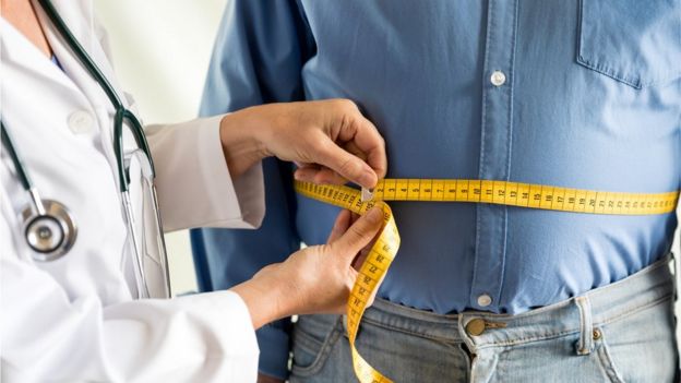 Uma médica mede o abdômen de um homem