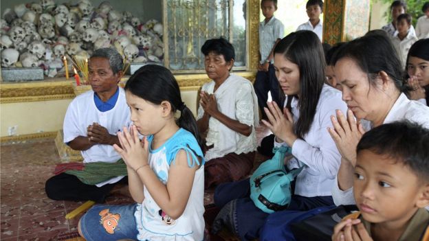 Cambodian people pray to Buddhist monks in front of skulls, at a pagoda in Takeo Province some 35 kilometres south-east of Phnom Penh, 04 October 2007.