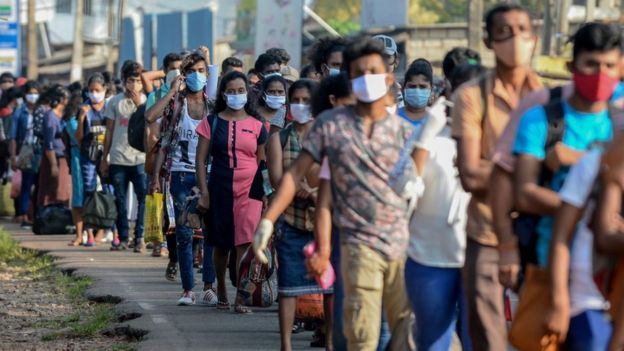 Workers carrying their belongings queue to board buses to go back to their homes in province during a government-imposed nationwide lockdown as a preventive measure against the COVID-19 coronavirus, at an industrial zone on the outskirts of Colombo on March 28, 2020.